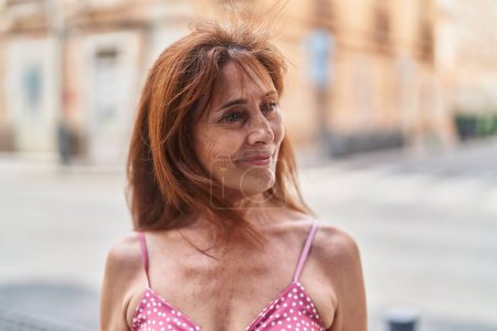 Téléchargez les photos : Femme d'âge moyen souriant confiant regardant vers le côté à la rue - en image libre de droit