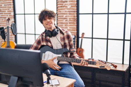 Foto de Joven músico hispano tocando la guitarra eléctrica en el estudio de música - Imagen libre de derechos