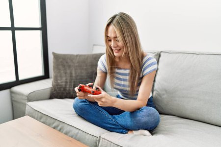Photo for Young chinese woman smiling confident playing video game at home - Royalty Free Image