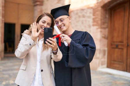 Photo for Man and woman mother and graduated son hugging each other having video call at university - Royalty Free Image