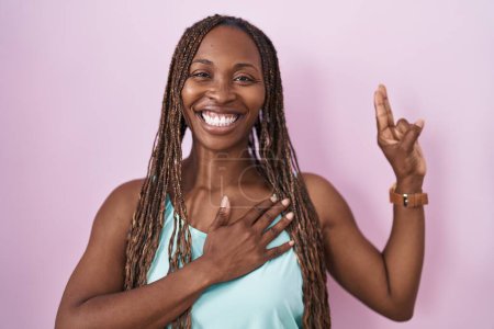 Téléchargez les photos : African american woman standing over pink background smiling swearing with hand on chest and fingers up, making a loyalty promise oath - en image libre de droit
