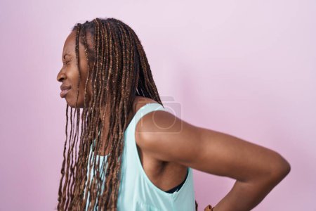 Téléchargez les photos : African american woman standing over pink background suffering of backache, touching back with hand, muscular pain - en image libre de droit