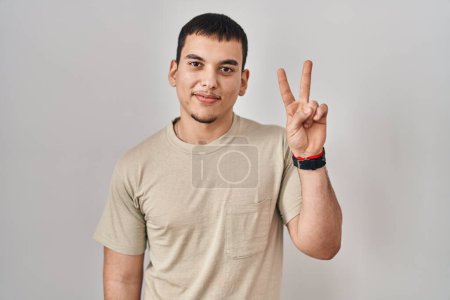 Téléchargez les photos : Jeune homme arabe portant t-shirt décontracté montrant et pointant vers le haut avec les doigts numéro deux tout en souriant confiant et heureux. - en image libre de droit