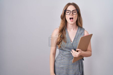 Téléchargez les photos : Femme blanche portant des lunettes et des vêtements de travail en colère et fou hurlant frustré et furieux, criant de colère. rage et concept agressif. - en image libre de droit