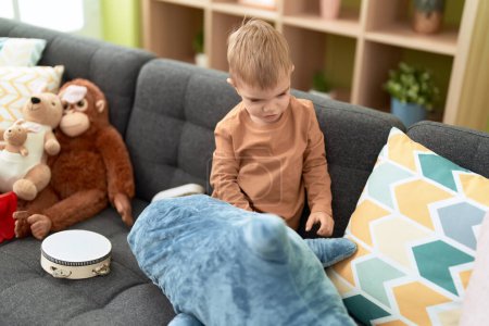 Foto de Adorable niño jugando con muñecas sentadas en el sofá en casa - Imagen libre de derechos
