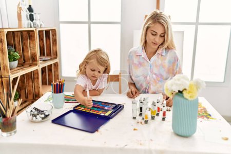 Téléchargez les photos : Mother and daughter smiling confident drawing on notebook at art studio - en image libre de droit