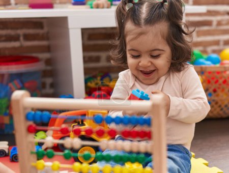 Photo for Adorable hispanic girl playing with abacus sitting on floor at kindergarten - Royalty Free Image
