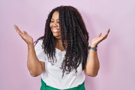 Photo for Plus size hispanic woman standing over pink background smiling showing both hands open palms, presenting and advertising comparison and balance - Royalty Free Image