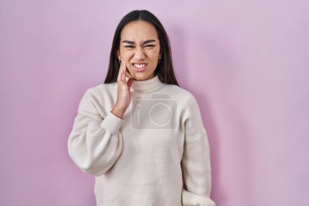 Foto de Young south asian woman standing over pink background touching mouth with hand with painful expression because of toothache or dental illness on teeth. dentist - Imagen libre de derechos