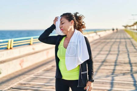 Photo for Middle age hispanic woman working out with towel for the sweat at promenade - Royalty Free Image
