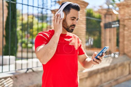 Photo for Young hispanic man listening to music at street - Royalty Free Image
