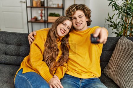 Téléchargez les photos : Jeune couple caucasien regarder film câlins à la maison - en image libre de droit