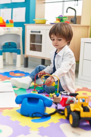 Téléchargez les photos : Adorable toddler playing toys sitting on floor at kindergarten - en image libre de droit