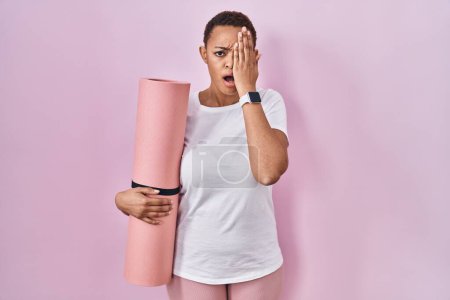 Téléchargez les photos : Beautiful african american woman holding yoga mat yawning tired covering half face, eye and mouth with hand. face hurts in pain. - en image libre de droit