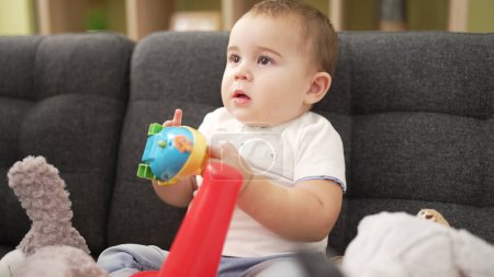 Foto de Adorable niño jugando con juguetes sentados en el sofá en casa - Imagen libre de derechos