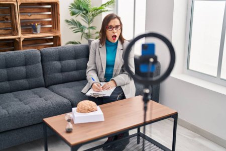 Photo for Middle age hispanic woman working at therapy office online scared and amazed with open mouth for surprise, disbelief face - Royalty Free Image