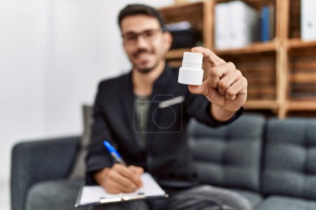 Photo for Young hispanic man having psychology session prescribe pills at clinic - Royalty Free Image