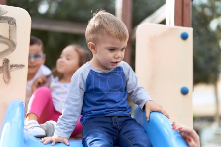 Téléchargez les photos : Adorable bambin souriant confiant jouant sur la glissière au terrain de jeu du parc - en image libre de droit