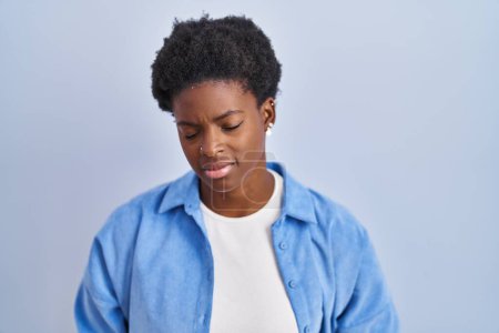 Téléchargez les photos : Femme afro-américaine debout sur fond bleu avec la main sur le ventre parce que l'indigestion, la maladie douloureuse se sent mal. concept de douleur. - en image libre de droit