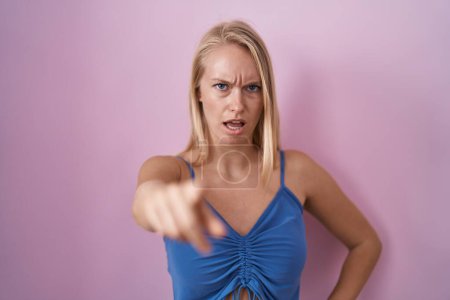 Foto de Young caucasian woman standing over pink background pointing displeased and frustrated to the camera, angry and furious with you - Imagen libre de derechos