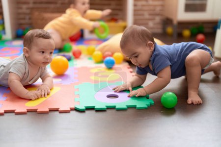 Foto de Grupo de niños pequeños que juegan con juguetes arrastrándose por el suelo en el jardín de infantes - Imagen libre de derechos