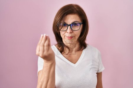 Foto de Mujer hispana de mediana edad de pie sobre fondo rosa haciendo gesto italiano con la mano y los dedos expresión de confianza - Imagen libre de derechos