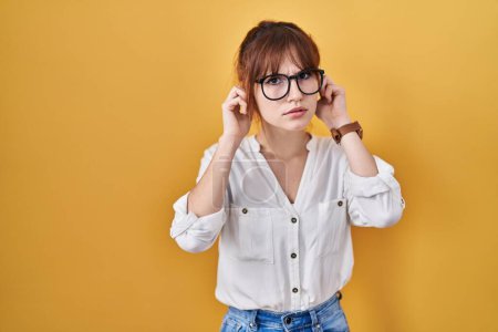 Photo for Young beautiful woman wearing casual shirt over yellow background covering ears with fingers with annoyed expression for the noise of loud music. deaf concept. - Royalty Free Image
