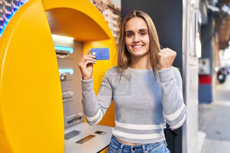Photo for Young doctor woman holding credit card at cash point screaming proud, celebrating victory and success very excited with raised arm - Royalty Free Image