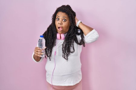 Photo for Plus size hispanic woman wearing sportswear and headphones crazy and scared with hands on head, afraid and surprised of shock with open mouth - Royalty Free Image