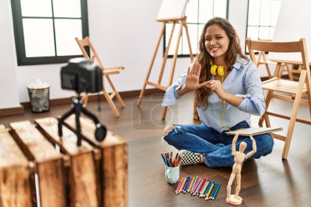 Photo for Young beautiful hispanic woman artist recording draw lesson communicate with deaf language at art studio - Royalty Free Image