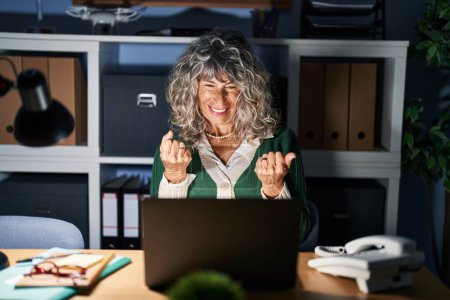 Photo for Middle age woman working at night using computer laptop very happy and excited doing winner gesture with arms raised, smiling and screaming for success. celebration concept. - Royalty Free Image