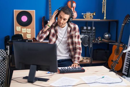 Téléchargez les photos : Young hispanic man musician having dj session at music studio - en image libre de droit