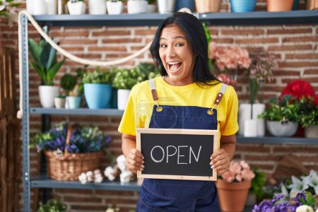Photo for Hispanic woman working at florist holding open sign celebrating crazy and amazed for success with open eyes screaming excited. - Royalty Free Image