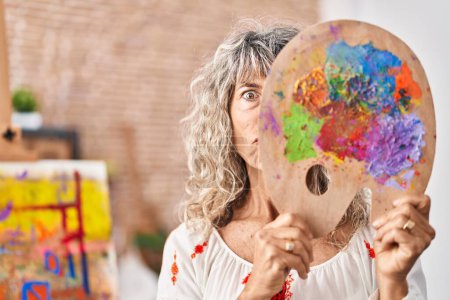 Foto de Middle age woman holding painter palette covering face skeptic and nervous, frowning upset because of problem. negative person. - Imagen libre de derechos