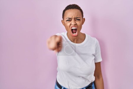 Téléchargez les photos : Belle femme afro-américaine debout sur fond rose pointant mécontent et frustré à la caméra, en colère et furieux contre vous - en image libre de droit