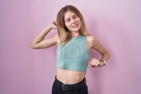 Photo for Blonde caucasian woman standing over pink background stretching back, tired and relaxed, sleepy and yawning for early morning - Royalty Free Image