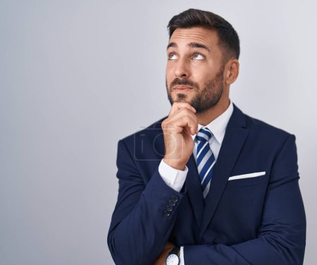 Photo for Handsome hispanic man wearing suit and tie with hand on chin thinking about question, pensive expression. smiling and thoughtful face. doubt concept. - Royalty Free Image