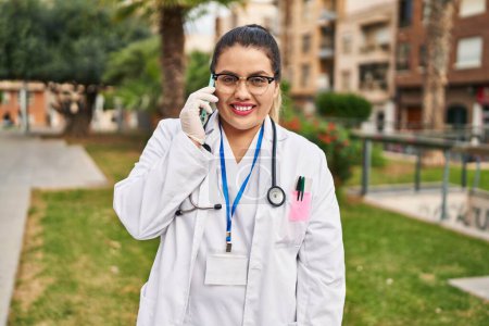 Téléchargez les photos : Young beautiful plus size woman doctor smiling confident talking on smartphone at park - en image libre de droit