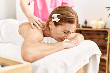 Téléchargez les photos : Moyen âge femme caucasienne ayant massage du dos au centre de beauté - en image libre de droit