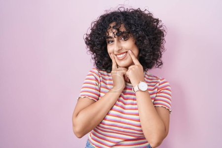 Téléchargez les photos : Young middle east woman standing over pink background smiling with open mouth, fingers pointing and forcing cheerful smile - en image libre de droit