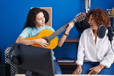 Photo for Two women musicians singing song playing classical guitar at music studio - Royalty Free Image