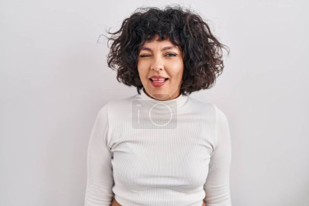 Photo for Hispanic woman with curly hair standing over isolated background winking looking at the camera with sexy expression, cheerful and happy face. - Royalty Free Image