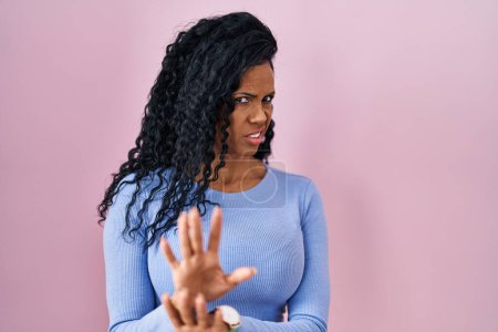 Téléchargez les photos : Middle age hispanic woman standing over pink background disgusted expression, displeased and fearful doing disgust face because aversion reaction. - en image libre de droit