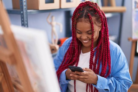 Téléchargez les photos : African american woman artist smiling confident using smartphone at art studio - en image libre de droit