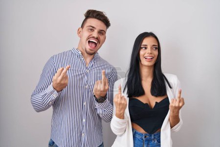 Foto de Young hispanic couple standing over white background showing middle finger doing fuck you bad expression, provocation and rude attitude. screaming excited - Imagen libre de derechos