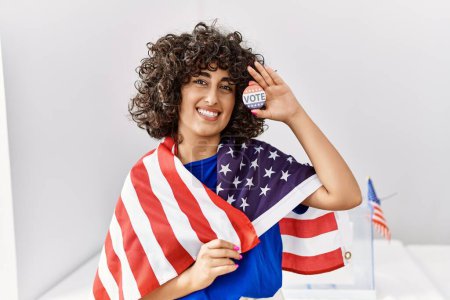 Téléchargez les photos : Jeune femme du Moyen-Orient portant le drapeau des États-Unis tenant un insigne de vote au collège électoral - en image libre de droit