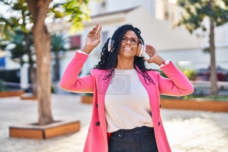Téléchargez les photos : Femme afro-américaine cadre à l'écoute de la musique et de la danse au parc - en image libre de droit