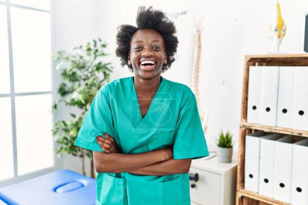 Photo for African young physiotherapist woman working at pain recovery clinic smiling and laughing hard out loud because funny crazy joke. - Royalty Free Image
