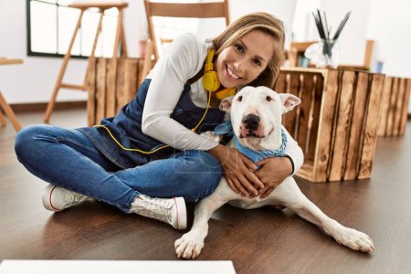 Téléchargez les photos : Jeune femme caucasienne souriant chien câlin confiant au studio d'art - en image libre de droit