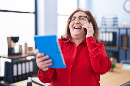 Téléchargez les photos : Travailleuse d'entreprise senior utilisant le pavé tactile parlant sur smartphone au bureau - en image libre de droit